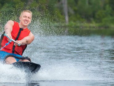 man on kneeboard kneeboarding on lake