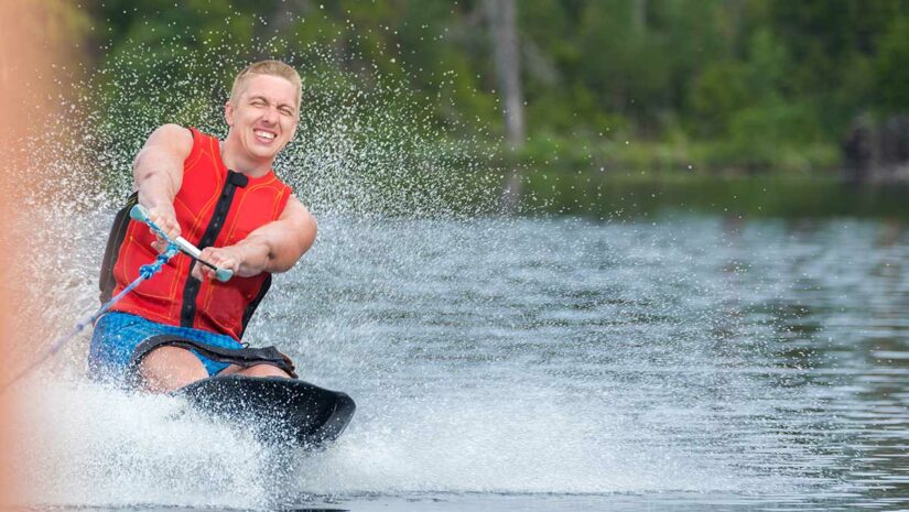 man on kneeboard kneeboarding on lake