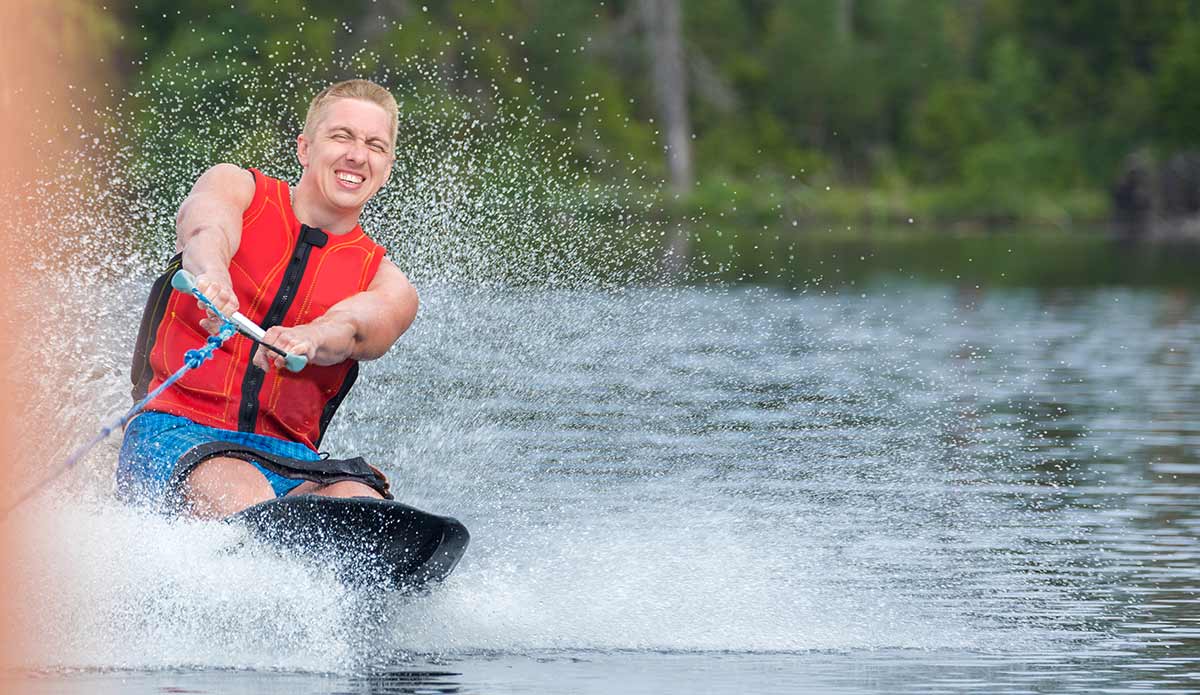 man on kneeboard kneeboarding on lake