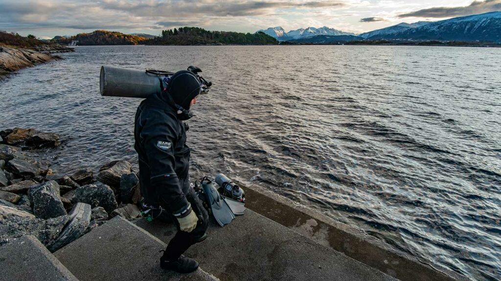 scuba diver getting ready to dive wearing bare drysuit