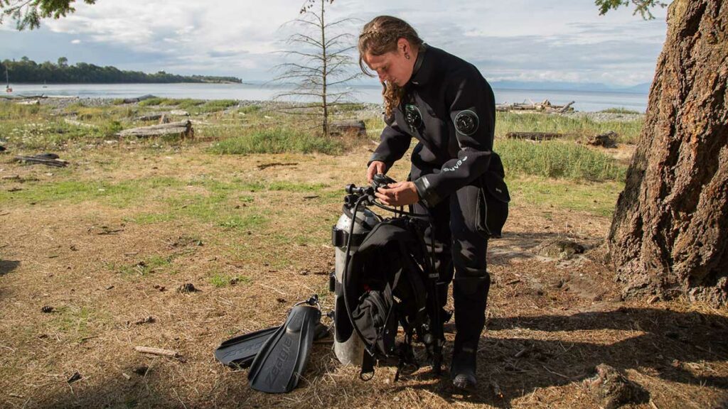 scuba diver getting ready to dive wearing bare drysuit