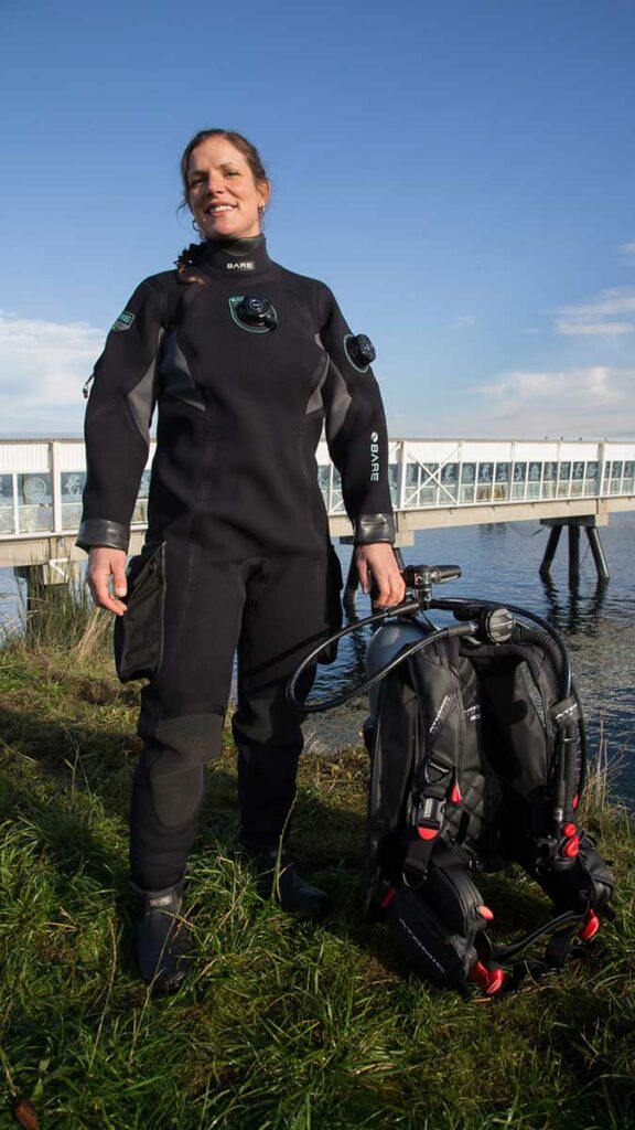 scuba diver getting ready to dive wearing bare drysuit
