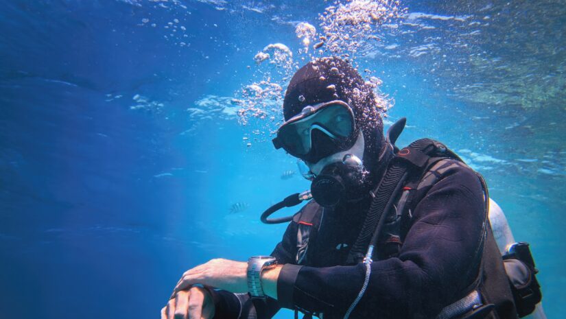Fully equipped man scuba diver using the 120 rule underwater in the blue water