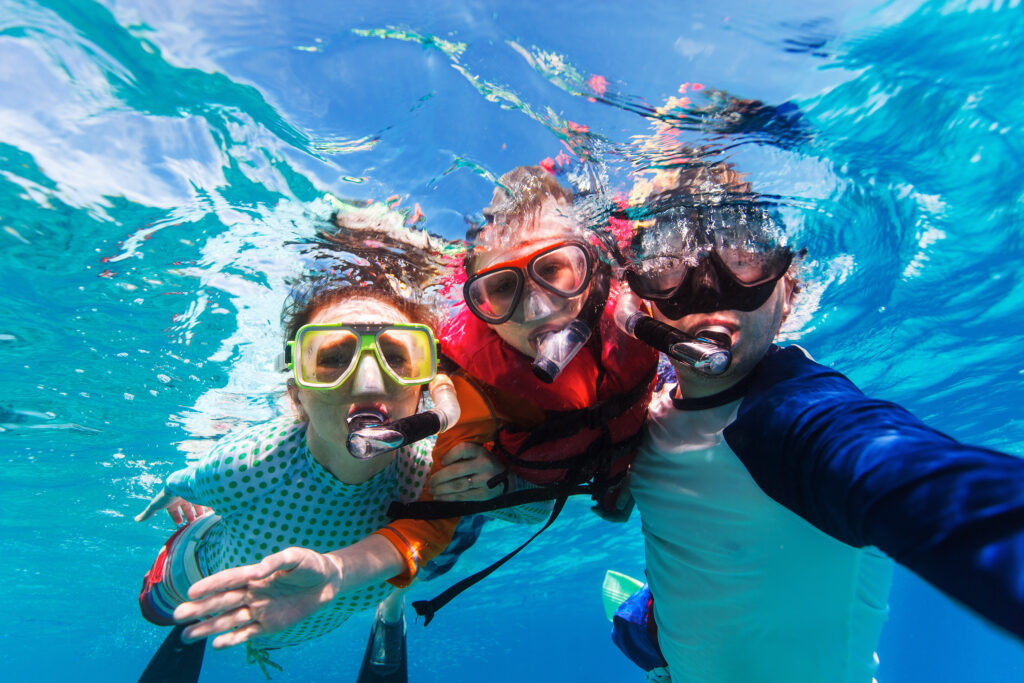 Underwater portrait of family snorkeling together at clear tropical ocean at a kid-friendly dive location