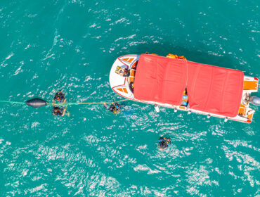 Boat with people diving suit mask and fins in the sea arrived in the lagoon to dive to the bottom, aerial top view