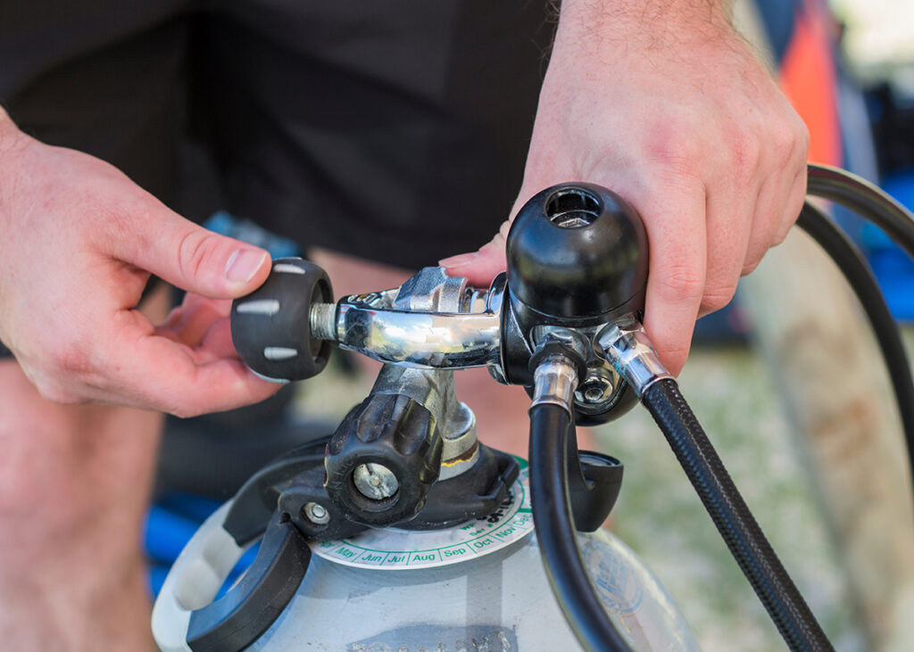 Scuba diver kitting up and checking the pressure gauge, close up of a hand holding equipment.
