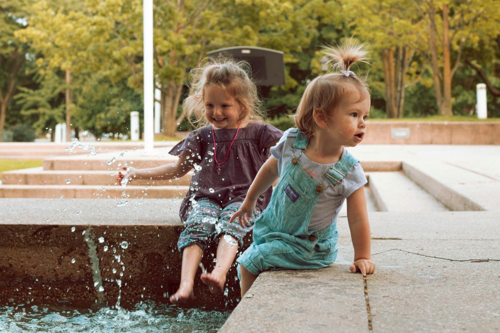 babies near sprinklers and a pool