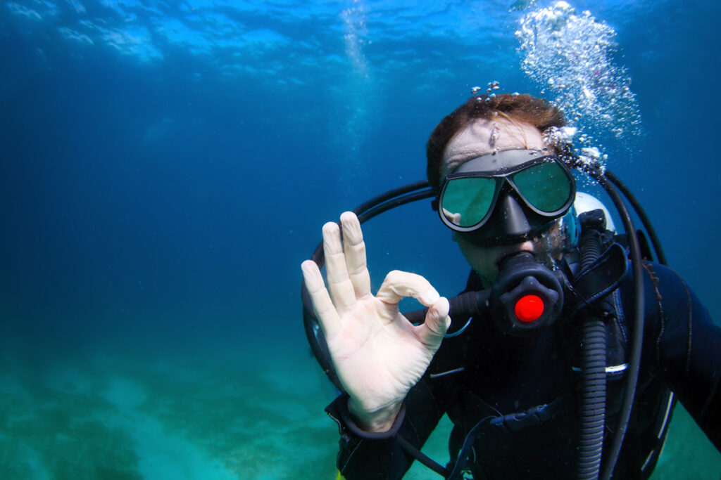 Underwater shoot of a man diving with scuba and showing ok signal