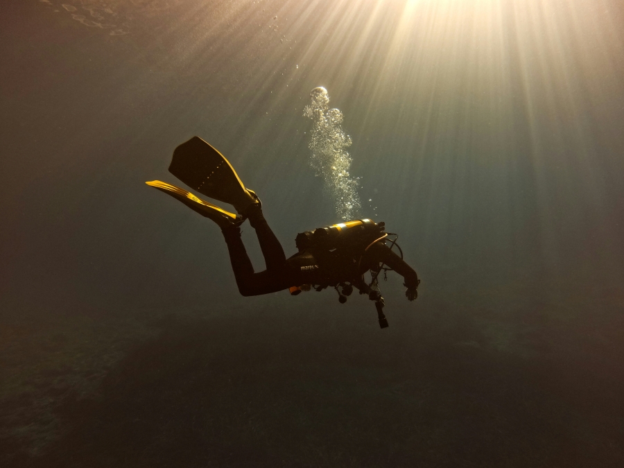 man drift diving with the sun shining through the surface