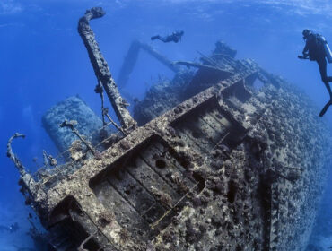 Divers exploring the outside of a shipwreck