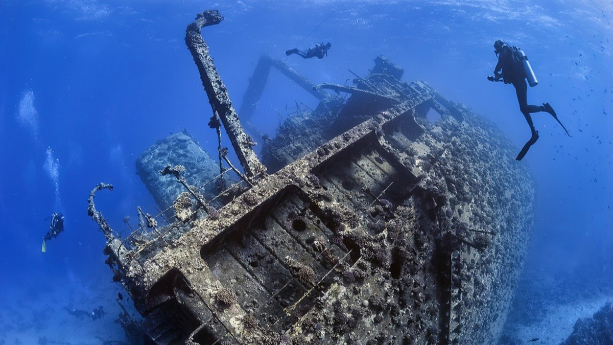 Divers exploring the outside of a shipwreck