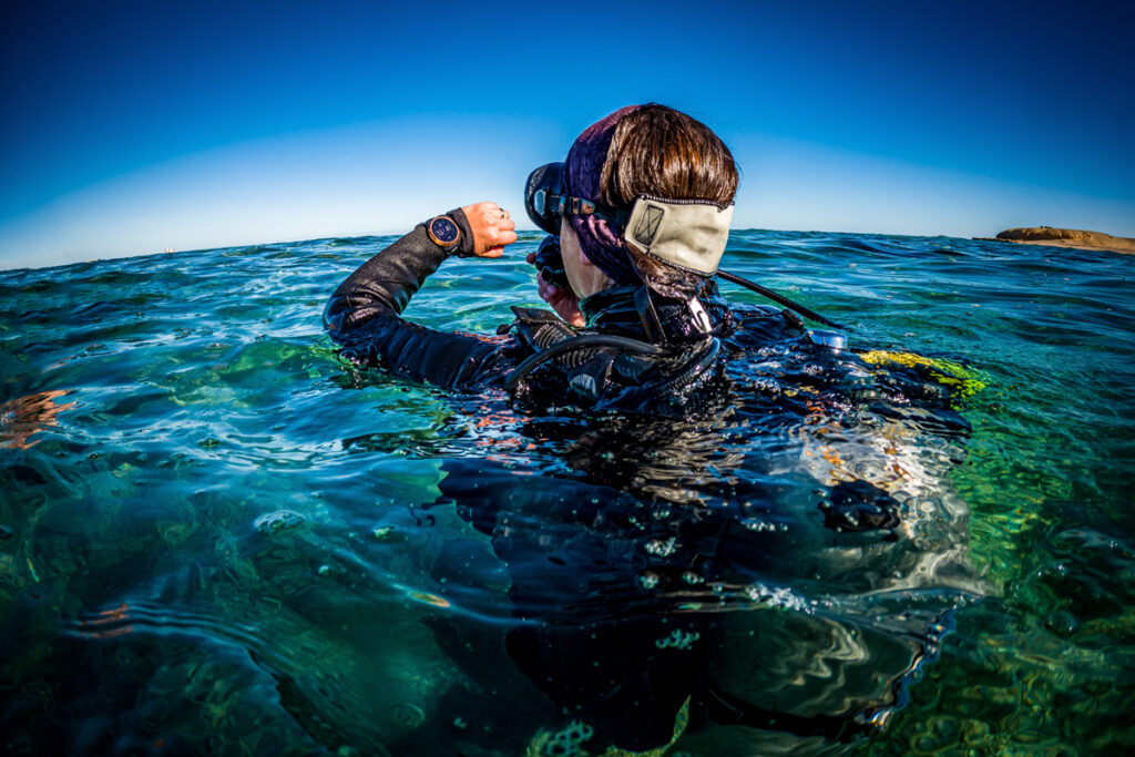 Scuba Diver Checks Dive Computer on Ocean Surface