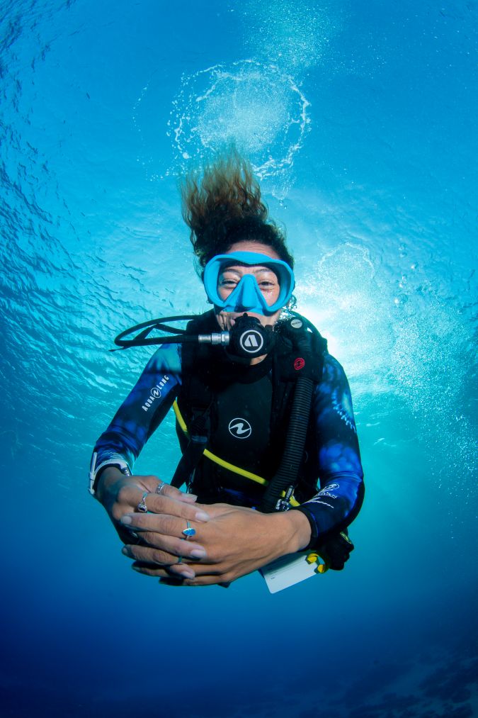underwater photo of a happy woman fully equipped with diving equipment