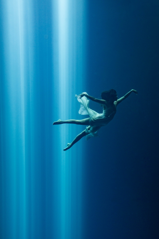 underwater photography model poses freely beyond a ray of light
