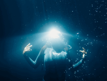 underwater model poses for the camera with a glowing light