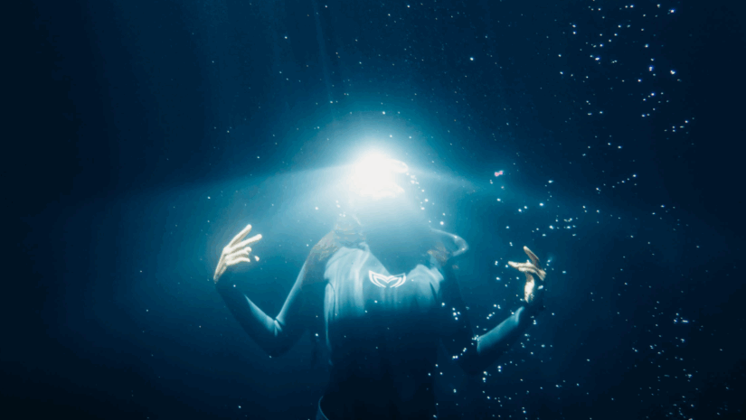 underwater model poses for the camera with a glowing light