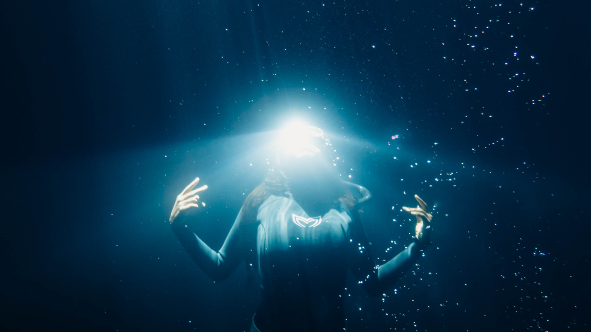 underwater model poses for the camera with a glowing light