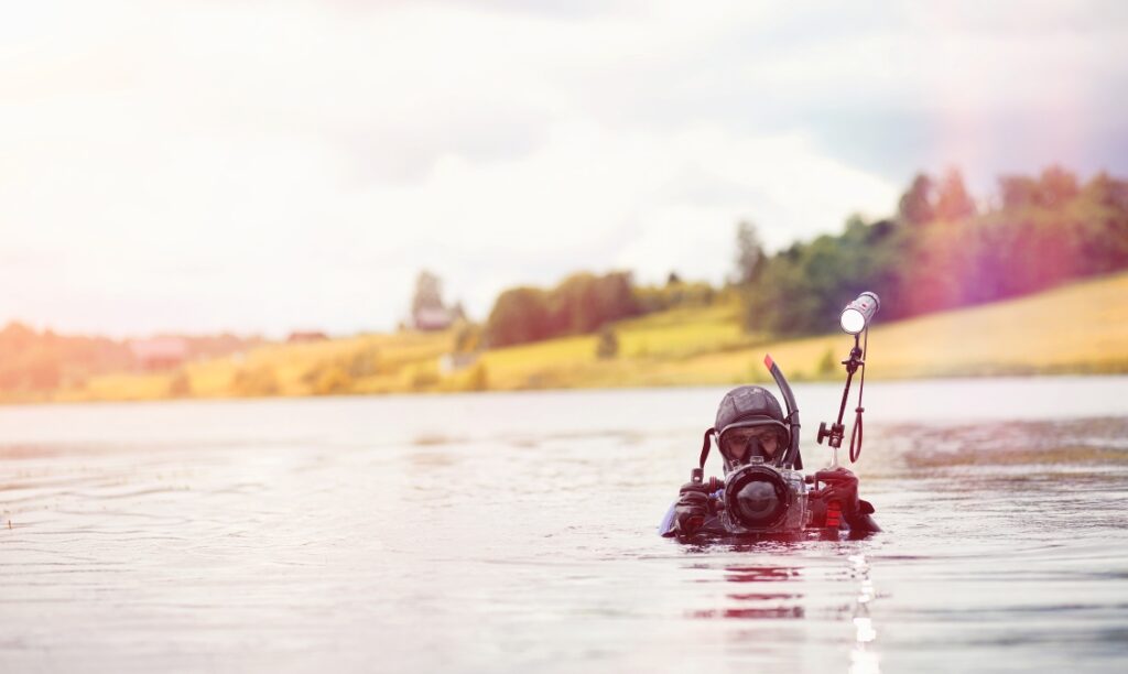 diver holds a camera with underwater housing