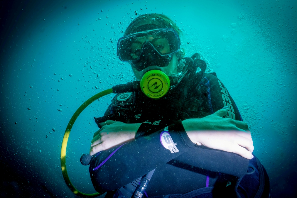 young female scuba diver makes gesture of being cold