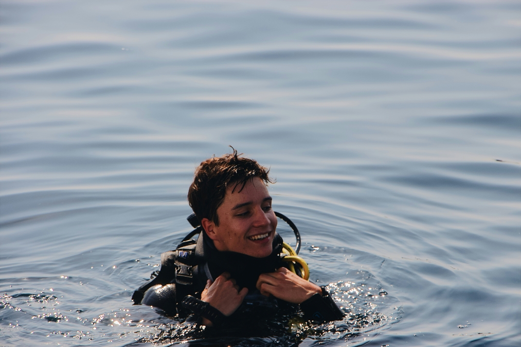 young male diver smiles at the surface with his scuba diving gear