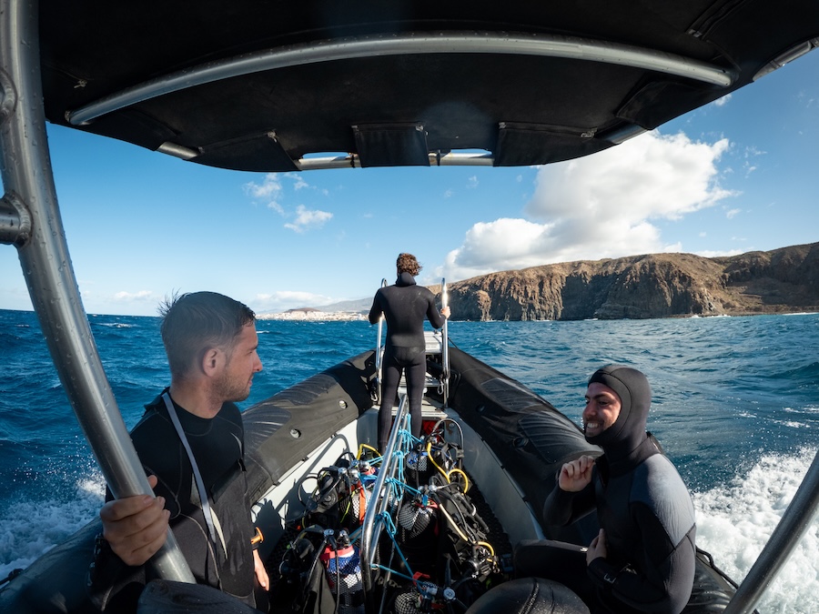 Scuba divers preparing their equipment on an inflatable boat, sailing towards the coast for a diving excursion