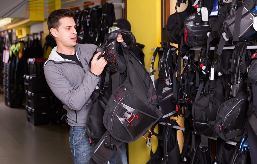 Young man is satisfied of diving equipment in the store