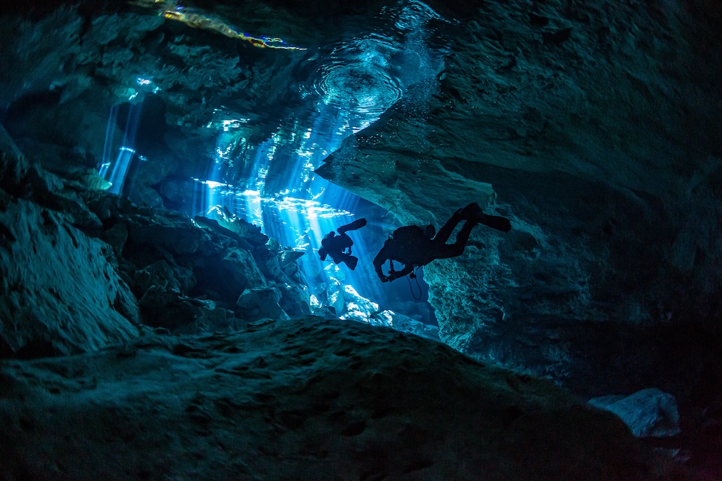 two cave divers moving towards the surface