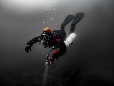 a fully equipped diver underwater wearing a BCD, oxygen tank, mask, and more