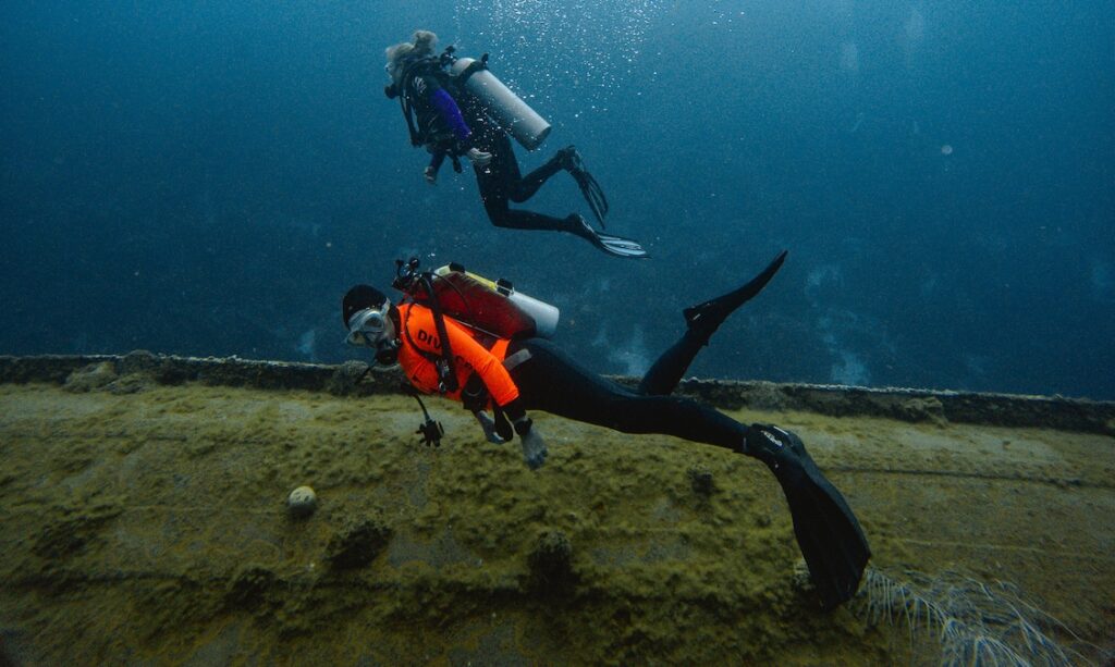 two divers diving along a wreck