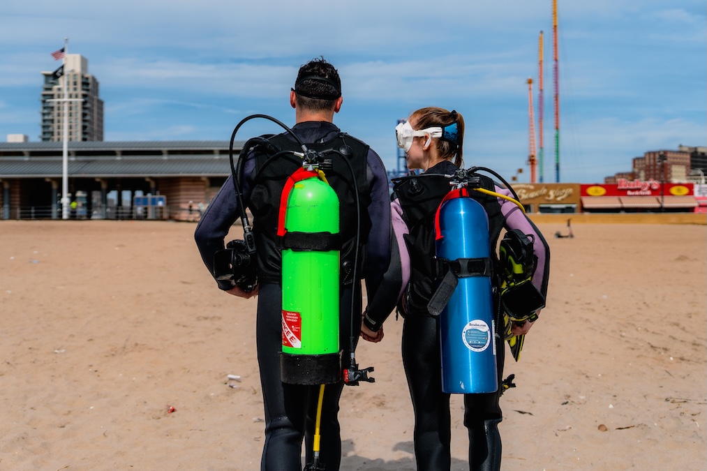 male and female scuba divers heading to the ocean fully equipped